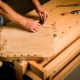 Handarbeit an einem Gitarrenhals mit Werkzeugen auf einem Holzarbeitsplatz, Fokus auf Holzverarbeitung und Handwerkskunst.