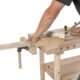 Person benutzt ein Holz- und Metallrollgerüst für präzise Arbeiten an einer Werkbank.