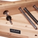 Befestigungselemente und Zubehör für das Mein Rollgerüst, inklusive Schrauben und Holzbohlen, auf einer Werkbank.