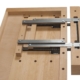 Holzwerkzeug für den Bau von Rollgerüsten, mit Führungsschienen und Griffen, auf einer Holzarbeitsplatte.
